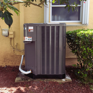 Residential central AC outdoor unit installed next to a yellow home.